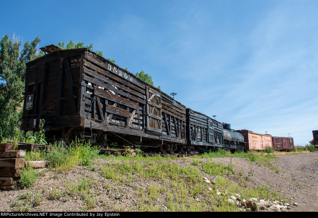 Two livestock cars and other peices of narrow gauge rolling stock sit on display at the Colorado Railroad Museum